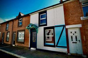 a brick building with a white door and windows at Victoria Titanic 1912 cottage in Belfast