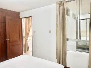 1 dormitorio con 1 cama y puerta de madera en Apartamento en el Centro de Trujillo - Primer Piso, en Trujillo