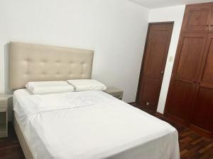 1 dormitorio con cama blanca y puerta de madera en Apartamento en el Centro de Trujillo - Primer Piso en Trujillo