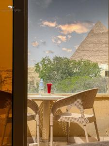 un tavolo con sedie e vista sulle piramidi di Giza Pyramids View Inn a Il Cairo