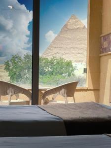 Habitación con cama y pirámide a través de una ventana en Giza Pyramids View Inn, en El Cairo