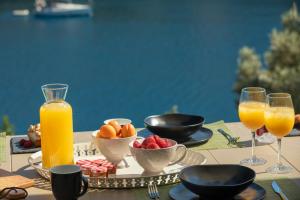 una mesa con una bandeja de fruta y vasos de zumo de naranja en Villa Olea-Brand New Luxury Villa, en Sivota