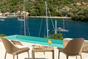 a patio with chairs and a table with a glass of wine at Villa Olea-Brand New Luxury Villa in Sivota