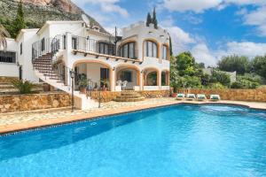 a villa with a swimming pool in front of a house at Olivo in Jávea
