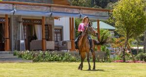 a woman riding a horse in front of a house at W15 Lake Gregory in Nuwara Eliya