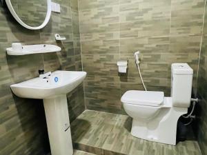 ein Badezimmer mit einem Waschbecken, einem WC und einem Spiegel in der Unterkunft Jaffna Palmyrah Hotel in Jaffna