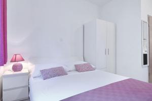 a white bedroom with a white bed and a pink lamp at Apartments BoBo in Kraj