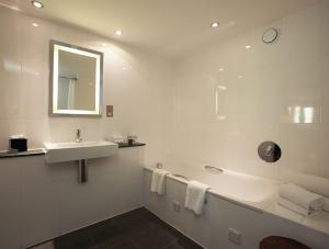a white bathroom with a sink and a bath tub at Salthouse Harbour Hotel and Spa in Ipswich +41 photos