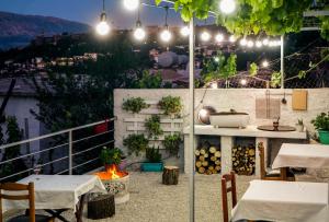a patio with tables and a fire pit on a balcony at night at Patio Rooms Gjirokaster in Gjirokastër