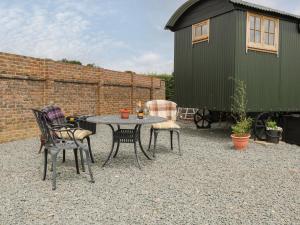 a patio with a table and chairs and a building at Shepherds Hut in Lewes