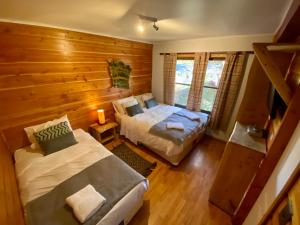 1 dormitorio con 2 camas en una habitación de madera en Hotel Andes Pucón, en Pucón