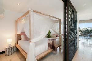 a bedroom with a canopy bed and a balcony at 128 Santai - Stylish Resort Apartment by uHoliday in Casuarina