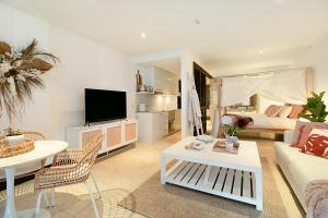 a living room with a couch and a table at 128 Santai - Stylish Resort Apartment by uHoliday in Casuarina +10 photos