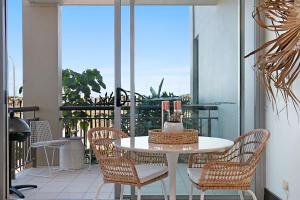a white table and chairs on a balcony at 128 Santai - Stylish Resort Apartment by uHoliday in Casuarina