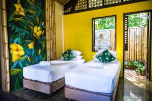 two beds in a room with a painting on the wall at Fox & The Firefly Cottages in Loboc