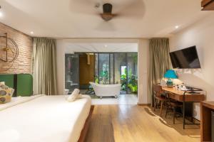 a bedroom with a bed and a desk and a tub at Seaforest Hotel by Haviland in Da Nang