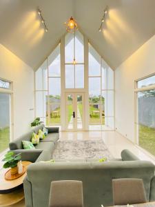 a living room with couches and a table and windows at Karabineri Private Pool Jogja Villa in Ngaglik