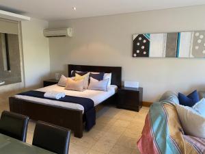 a bedroom with a bed with pillows and a couch at 208 Santai - Spacious Family Apartment by uHoliday in Casuarina