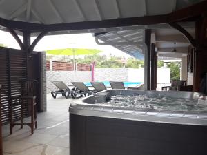 a hot tub on a patio with chairs and an umbrella at Aux petits flots in Le Gosier
