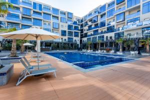 a swimming pool with a chair and an umbrella next to a building at Live in style. Luxury destination - OIA - Motor City in Dubai