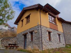 ein gelbes Gebäude mit einem Holzdach in der Unterkunft Casa Rural La Cabaña del Valleyu in Sotres