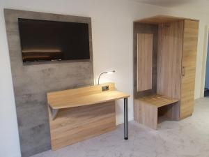 a wooden desk with a tv on a wall at hb-Gästehaus 