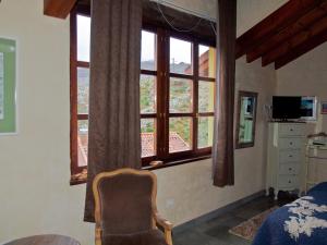 a bedroom with a chair and a large window at Casa Rural La Cabaña del Valleyu in Sotres