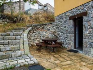 una mesa de picnic sentada fuera de un edificio de piedra en Casa Rural La Cabaña del Valleyu, en Sotres