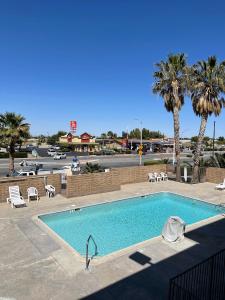 a swimming pool in a parking lot with palm trees at Palms Inn & Suites in Palmdale