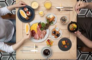 een groep mensen die rond een tafel zitten met ontbijtproducten bij Nagoya JR Gate Tower Hotel in Nagoya