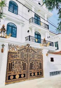 Um edifício branco com um portão dourado à frente. em Pallas Villa em Vung Tau