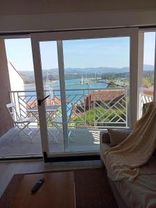een woonkamer met een glazen schuifdeur naar een balkon bij Apartamentos Costa San Esteban in San Esteban de Pravia
