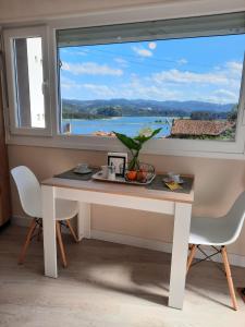 a table and chairs in front of a large window at Apartamentos Costa San Esteban in San Esteban de Pravia