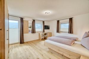 a bedroom with a bed with a desk and windows at Apart Bock in Stanz bei Landeck