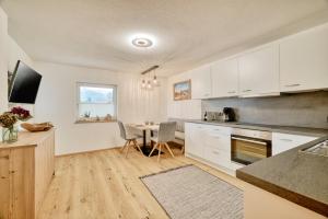 uma cozinha com armários brancos e uma mesa com cadeiras em Apart Bock em Stanz bei Landeck