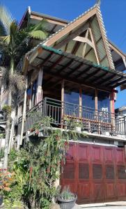 a house with a red door and a balcony at Smiley's Homestay in Berastagi