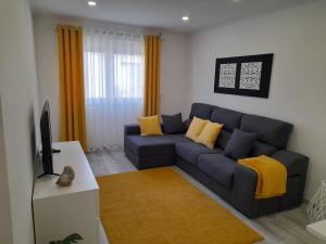 ein Wohnzimmer mit einem blauen Sofa und gelben Kissen in der Unterkunft PENICHE SWEET HOME in Peniche