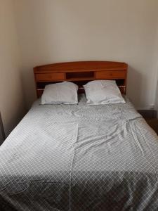 a bed with a wooden headboard and two pillows at Maison de ville proche beauval avec parking in Selles-sur-Cher