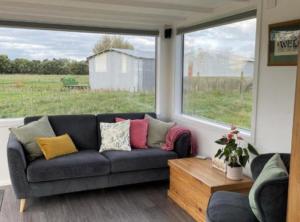 a living room with a couch and a large window at The Tiny Nest in Palmerston North