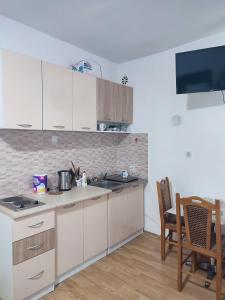 a kitchen with white cabinets and a table and a television at Apartment Marija Bar in Bar