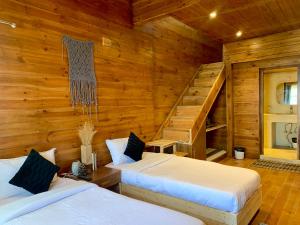 two beds in a room with wooden walls at Sugar Cube Retreat in Shimla