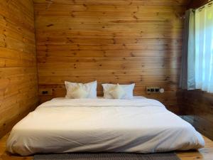 um quarto com uma cama branca numa parede de madeira em Sugar Cube Retreat em Shimla