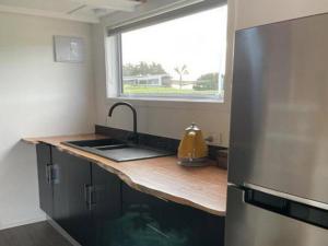 a kitchen with a sink and a refrigerator and a window at The Tiny Nest in Palmerston North