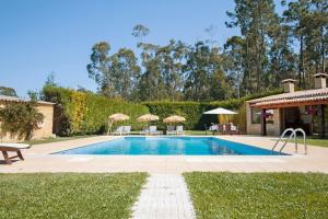 a swimming pool with chairs and umbrellas in a yard at VILLA 500 in Barcelos