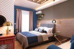 a bedroom with a bed with a blue wall at ELLE Rooms & Suites in Paralia Katerinis