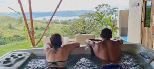 dos personas sentadas en un jacuzzi leyendo libros en Essence Arenal Spa & Yoga, en El Castillo de La Fortuna