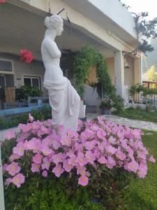 une statue d'une femme dans un lit de fleurs roses dans l'établissement Blue Dreams, à Almiropótamos