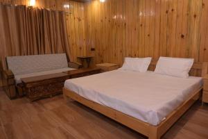 a bedroom with a bed and a bench and wooden walls at Hotel Royal Hillcrest in Harsil