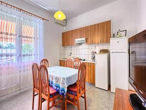 cocina con mesa, sillas y nevera en Apartment Lucija, en Kaštela