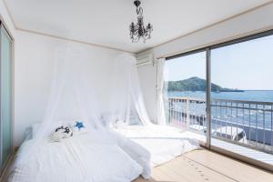 een slaapkamer met een bed en een groot raam bij Marine House KAKISAKI in Shimoda
